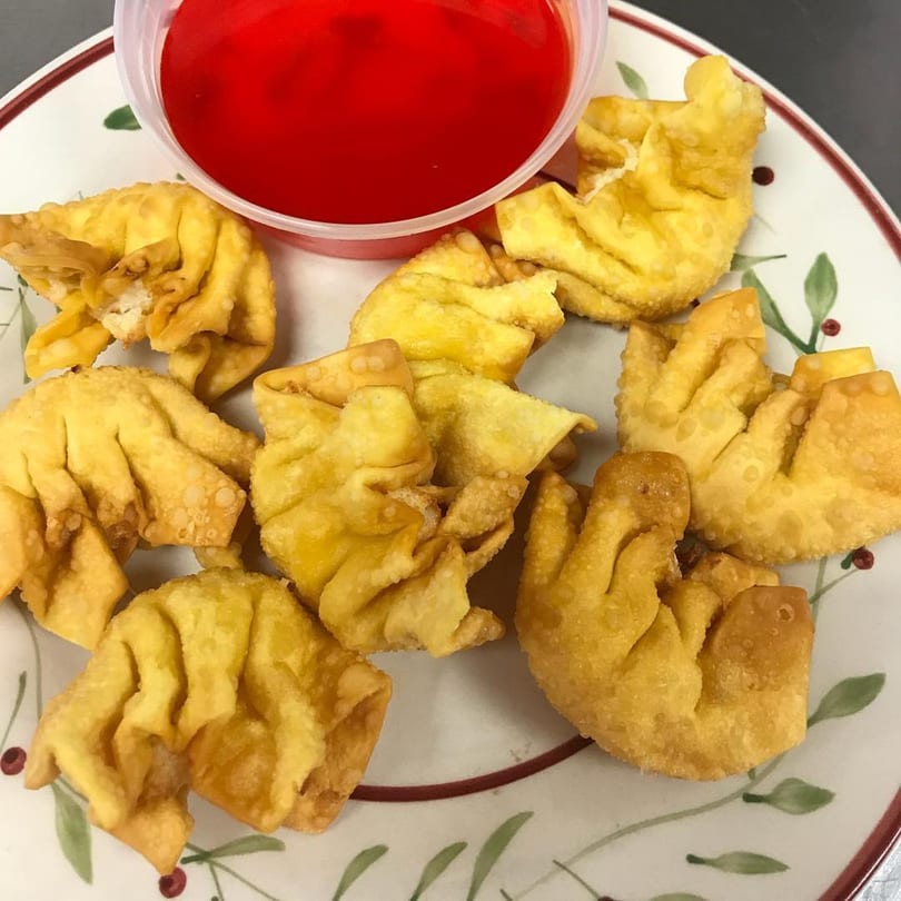 Golden fried crab rangoons from China Star, served with a side of bright red sweet and sour sauce.