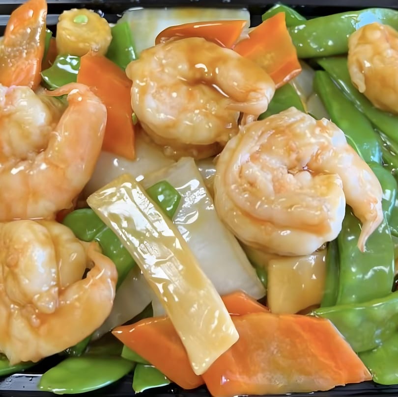 Shrimp with mixed vegetables, including snow peas, carrots, and water chestnuts, in a light sauce.