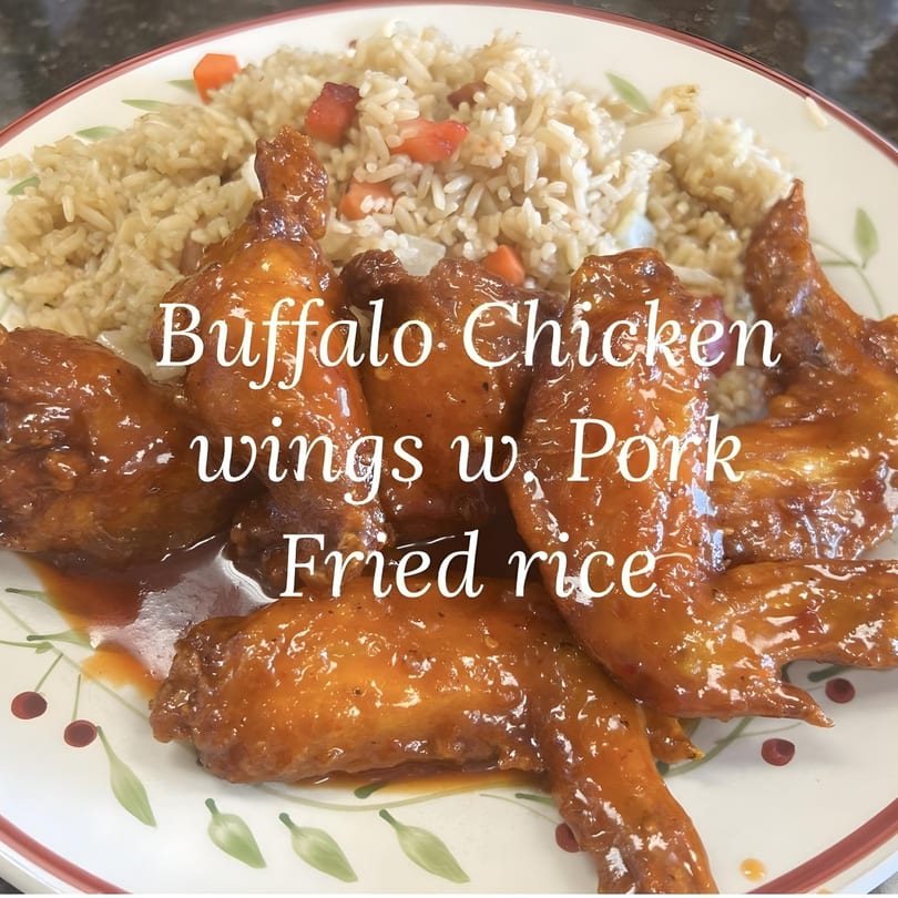 Buffalo chicken wings with pork fried rice on a white plate with a cherry design.