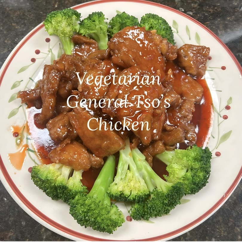 Vegetarian General Tso's Chicken with broccoli florets on a white plate with red trim.