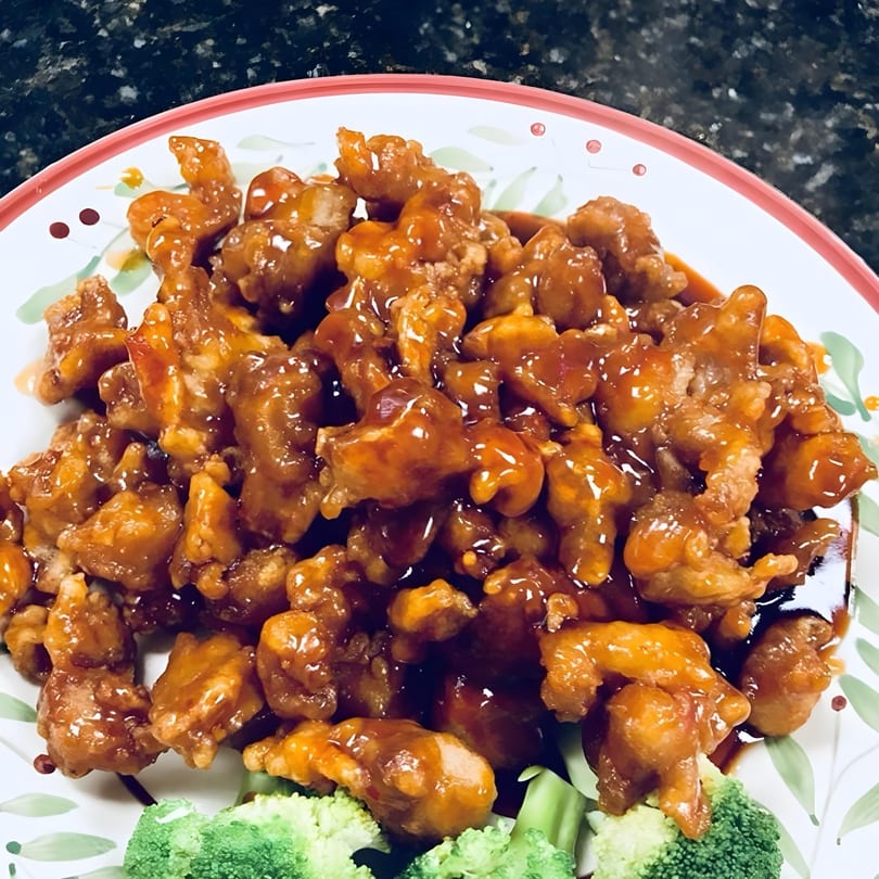 Close-up of China Star's orange chicken, glistening with sauce, served with fresh broccoli.